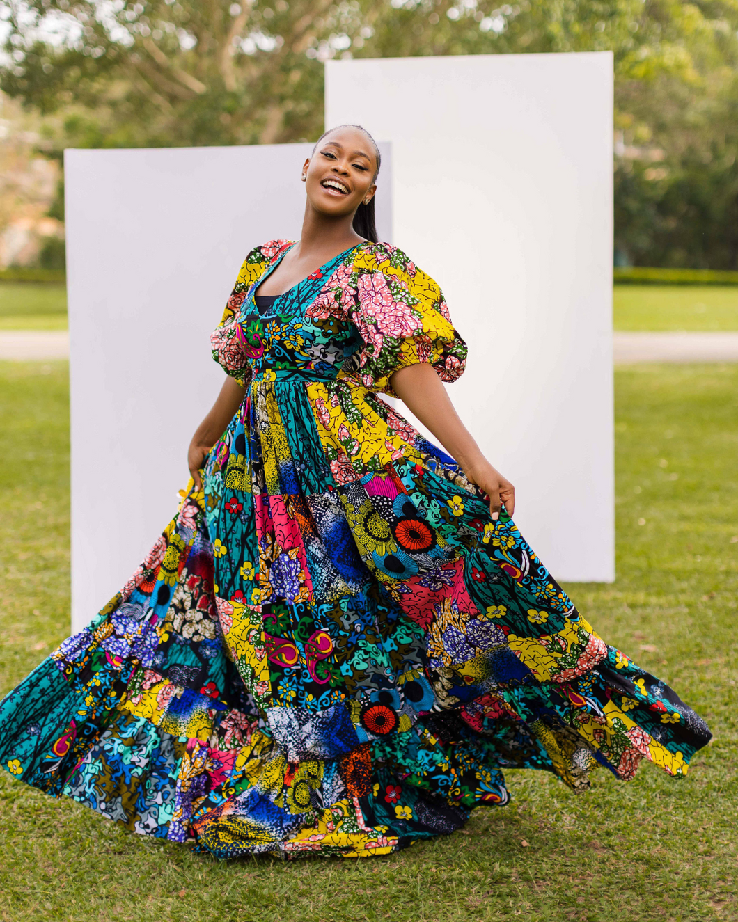 Hand crafted Deep V neckline Deep back cut-out with tie detail Cinched waistline Fitted bodice Full elasticized bell sleeves 2-tier gathered base Patchwork Maxi dress Side Pockets African print (Ankara)